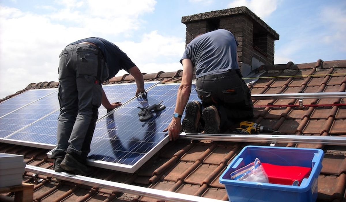 two roofing professionals installing solar panel on a roof