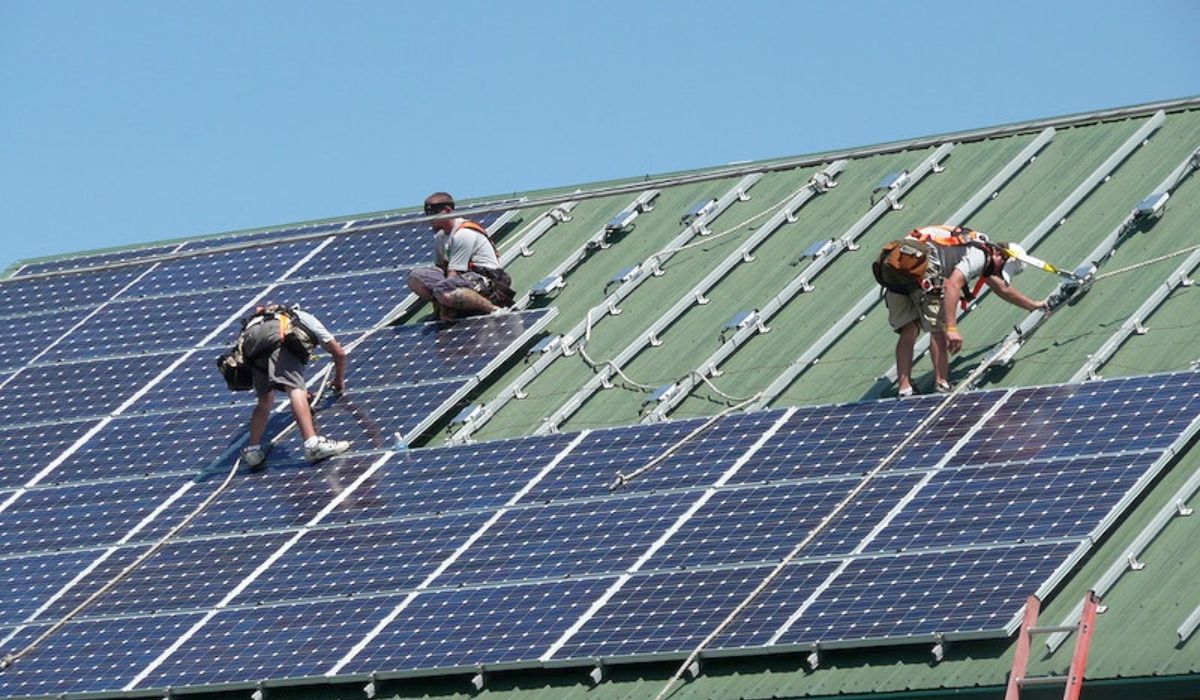 the three roofers installing the solar panels on large roof
