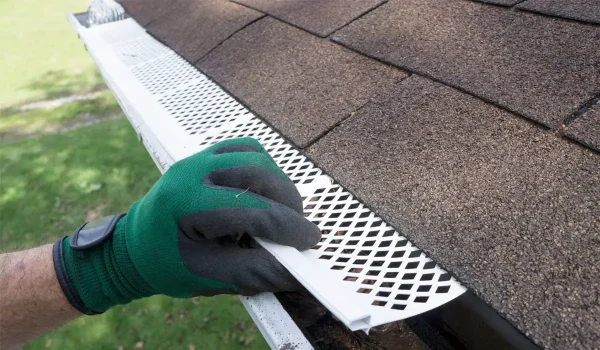 contractor fixing the plastic gutter guard to fit the rain gutter
